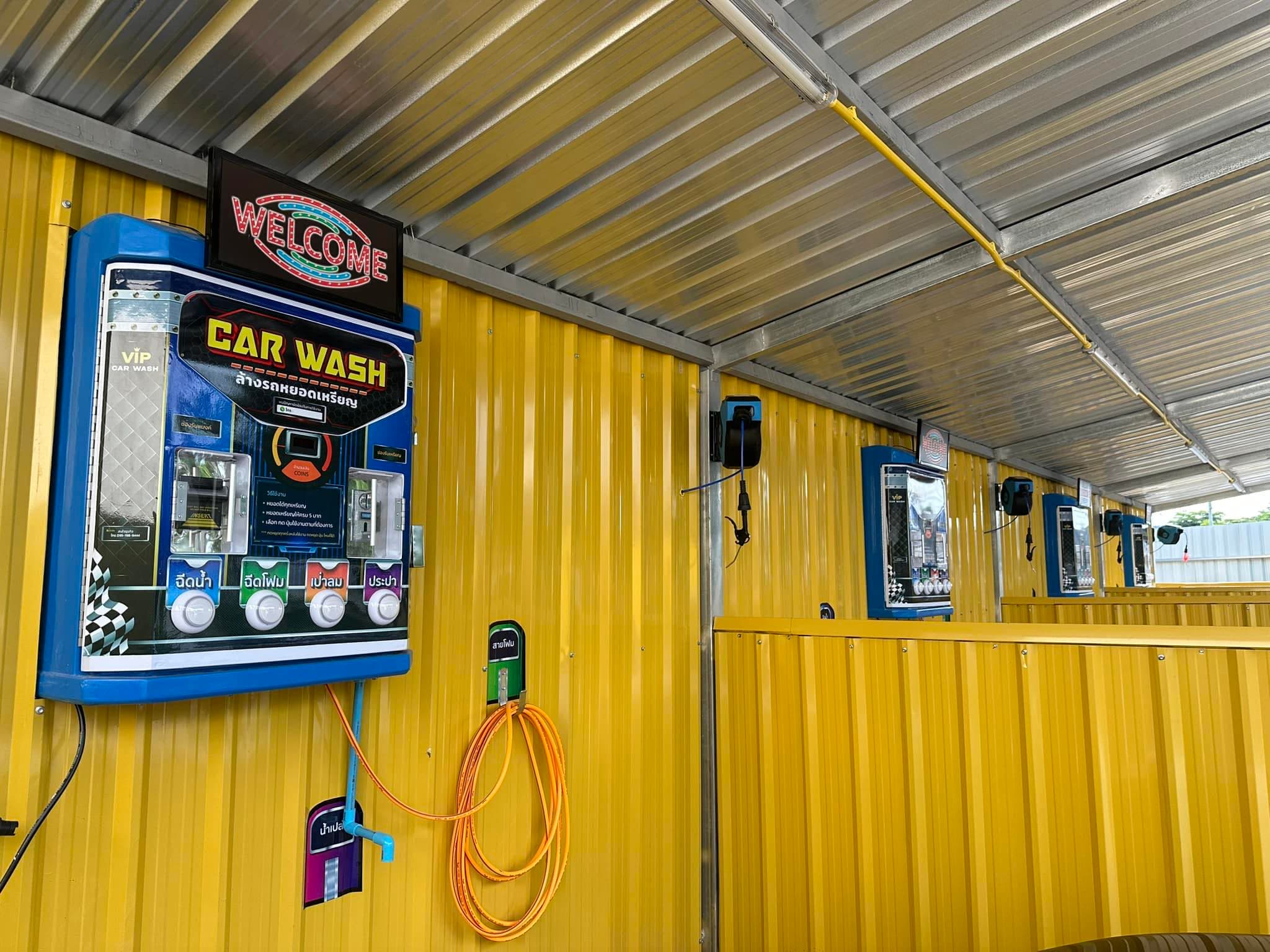 ป้าย Welcome และตู้หยอดเหรียญ CAR WASH ของ P Selfwash บ้านเลื่อม อุดรธานี ในบรรยากาศช่องล้างรถสีเหลืองสว่าง (P Selfwash welcome sign and CAR WASH coin terminal at the yellow self-service bay in Ban Lueam, Udon Thani)