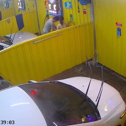 มุมกว้างของบริเวณ P Selfwash ขณะมีลูกค้าใช้บริการ หันหลังกำลังล้างรถ (Wide view of P Selfwash during operation with back-turned customers washing their cars)